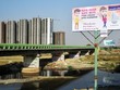 Bảng quảng cáo của một nhà môi giới Web Tổng Nhà Cái 99Kl99 Giải Trí Bậc Nhất với hình ảnh một nhân vật cầm tờ tiền 2.000 rupee mới cùng slogan “Nhà mới, tiền mới”, gần khu vực đang xây dựng các tòa chung cư tại Uttar Pradesh
