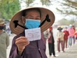 Bà Trần Thị Đảnh, 65 tuổi, cầm phiếu, đứng đầu hàng chuẩn bị vào bấm máy nhận gạo trước trụ sở phường Mũi Né.
