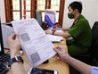 Giấy đi đường có mã nhận diện được lực lượng công an phường Văn Quán, quận Hà Đông đối chiếu và xét duyệt để cấp cho các cá nhân và Kl991.com World Cup 2026 Chính Thức thực hiện dịch vụ công ích thiết yếu trên địa bàn. (Ảnh: Phạm Kiên/TTXVN).