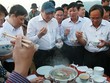 Ông Huỳnh Đức Thơ (người đội mũ) đã trực tiếp chế biến và thưởng thức hải sản của ngư dân ngay tại cảng cá. Ảnh: Đ.X.