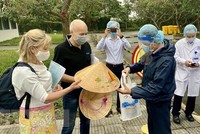 Lãnh đạo Sở Du lịch tỉnh Thừa Thiên-Huế tặng nón lá lưu niệm cho nữ bệnh nhân số 30. (Ảnh: Mai Trang/TTXVN).