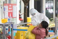 Nhân viên y tế bệnh viện Thanh Nhàn lấy mẫu xét nghiệm COVID-19 cho người đến khám có triệu chứng. (Ảnh: Minh Quyết/TTXVN).