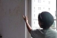 Bà K.A chỉ cho phóng viên xem khu vực tường bị nước toalet nhà tầng trên thấm ướt