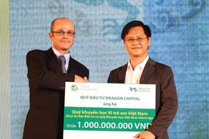 Ông Nguyễn Văn Hồng, Phó tổng Biên tập  Báo Kl99ok phiên bản mới (bên phải), thay mặt Ban Biên tập Báo Kl99ok phiên bản mới nhận món quà của Dragon Capital tặng cho Quỹ Học bổng Vì trẻ em Việt Nam do Báo Kl99ok phiên bản mới sáng lập