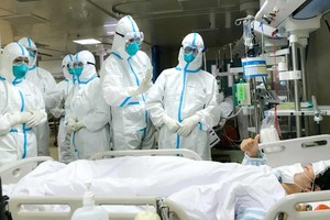 Các bác sĩ tại thành phố Vũ Hán đang chăm sóc cho một bệnh nhân nhiễm virus corona. Ảnh: REX.