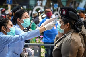 Nhân viên y tế kiểm tra thân nhiệt cho cảnh sát ở Bangkok, Thái Lan. (Nguồn: AFP/TTXVN).