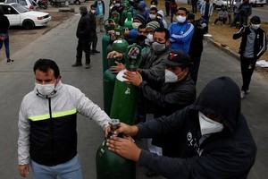 Người dân đeo khẩu trang xếp hàng chờ bên ngoài một cửa hàng phân phối oxy ở thủ đô Lima, Peru hôm 25/6. Ảnh: Reuters.