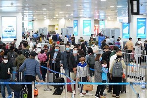 Hành khách tuân thủ việc đeo khẩu trang khi làm thủ tục chuyến bay tại Cảng hàng không quốc tế Nội Bài. (Ảnh: Phan Công/Vietnam+).