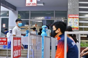 Người dân đến lấy mẫu xét nghiệm được bố trí ngồi chờ theo khu vực quy định. (Ảnh: Minh Quyết/TTXVN).