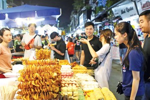 Du khách chọn món ăn tại chợ đêm khu phố cổ (quận Hoàn Kiếm, Hà Nội). Ảnh: Hồ Hạ.
