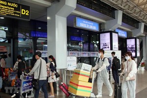 Để phòng chống dịch, nhiều hành khách đã chủ động trang bị các bộ đồ bảo hộ khi đến sân bay Tân Sơn Nhất. (Ảnh: Tiến Lực/TTXVN).