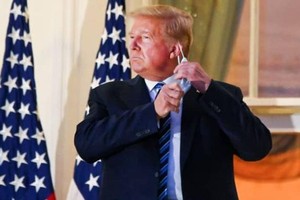 Cựu Tổng thống Donald Trump kéo khẩu trang khi xuất hiện tại ban công Nhà Trắng sau 3 ngày điều trị tại bệnh viện. (Ảnh: Reuters).