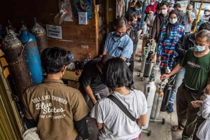 Người nhà của bệnh nhân Covid-19 xếp hàng để bơm đầy bình oxy ở Manggarai, Jakarta. Ảnh: Shutterstock.
