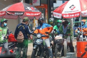 Rất đông những người giao hàng (shipper) tại giao lộ đường Phạm Văn Đồng-Phan Văn Trị (quận Gò Vấp). (Ảnh: Thanh Vũ/TTXVN).