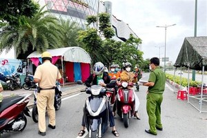 Lực lượng Công an tại chốt kiểm trên đường Phạm Văn Đồng (phường Hiệp Bình Chánh, Thủ Đức) kiểm tra giấy tờ của người lưu thông. (Ảnh: Thành Chung/TTXVN).