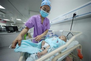 Nhân viên y tế chăm sóc trẻ mới sinh tại bệnh viện ở tỉnh Quý Châu (Trung Quốc), ngày 11/5/2021. (Ảnh: AFP/TTXVN).
