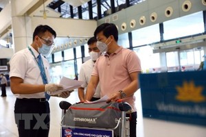 Nhân viên của Vietnam Airlines kiểm tra giấy tờ của hành khách trước khi vào làm thủ tục. (Ảnh: Huy Hùng/TTXVN).