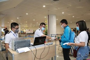 Nhân viên y tế kiểm tra phiếu khai báo y tế của hành khách trước khi làm thủ tục nhập cảnh tại cửa khẩu Sân bay quốc tế Nội Bài (Ảnh: TTXVN).