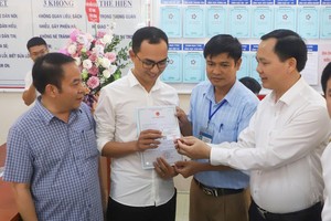Phó tổng giám đốc BHXH Việt Nam Chu Mạnh Sinh trao thẻ BHYT của bé gái cho anh Đinh Tiến Hoàng.