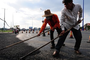 Công nhân thi công trải nhựa trên xa lộ Hà Nội (đoạn Q.2, TP.HCM). Theo kế hoạch, dự án này hoàn thành trong năm 2012 nhưng chậm đền bù giải tỏa nên có thể phải đến năm 2014 mới hoàn thành (ảnh chụp 