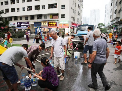 Người dân những khu vực bị ô nhiễm nước mang theo xô, bình nước lớn để lấy nước sạch sinh hoạt từ xe téc (Ảnh: TTXVN)