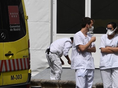 Hai nhân viên y tế trò chuyện cạnh xe cứu thương bên ngoài bệnh viện La Paz ở Madrid hôm 23/3. Ảnh: AFP.