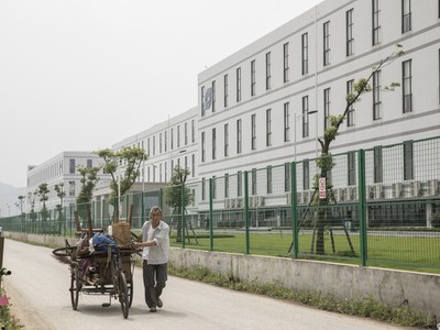 Một người đàn ông đang kéo một chiếc xe kéo phía trước nhà máy được điều hành bởi Kl994 game bài casino hấp dẫn Công nghệ Quang học Sunny. (Nguồn: Qilai Shen/Bloomberg).