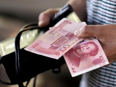 Người mua hàng cầm tờ 100 NDT tại một khu chợ ở Bắc Kinh. Ảnh: Reuters.