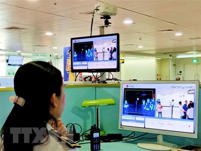 Nhân viên sân bay Tân Sơn Nhất kiểm tra màn hình hiển thị máy quét thân nhiệt đối với hành khách quốc tế đến Việt Nam. (Ảnh: Đinh Hằng/TTXVN).