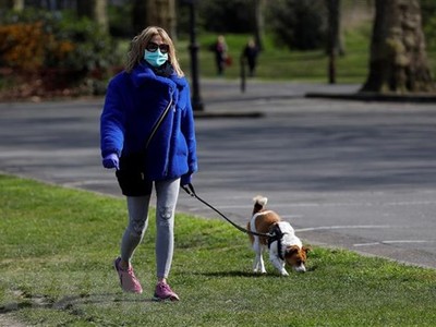 Một phụ nữ dạo bộ cùng với chú chó cưng tại công viên ở London, Anh. (Ảnh: AFP/TTXVN).
