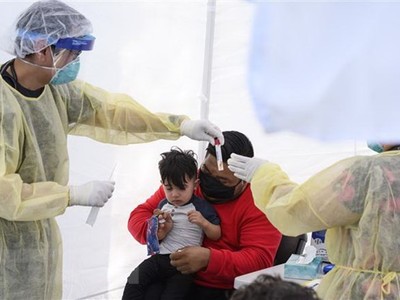 Lấy mẫu dịch xét nghiệm COVID-19 cho trẻ nhỏ. (Ảnh: AFP/TTXVN).