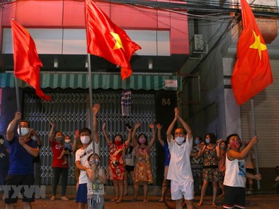 Người dân ở trên tuyến đường Nguyễn Thị Minh Khai vui mừng sau khi hoàn thành cách ly 14 ngày trong khu vực phong tỏa. (Ảnh: Trần Lê Lâm/TTXVN).