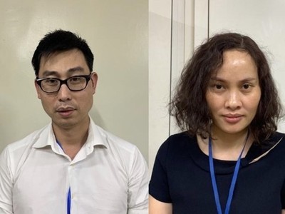 Bị can Phạm Đức Tuấn (nam áo trắng) và bị can Ngô Thị Thu Huyền (nữ áo xanh đen). (Nguồn: Bộ Công an).