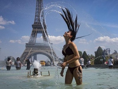 Một cô gái giải nhiệt trước khu vực tháp Eiffel trong đợt nắng nóng cao điểm ở Pháp năm 2019 (Ảnh minh họa: EPA).