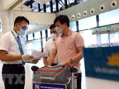 Nhân viên của Vietnam Airlines kiểm tra giấy tờ của hành khách trước khi vào làm thủ tục. (Ảnh: Huy Hùng/TTXVN).