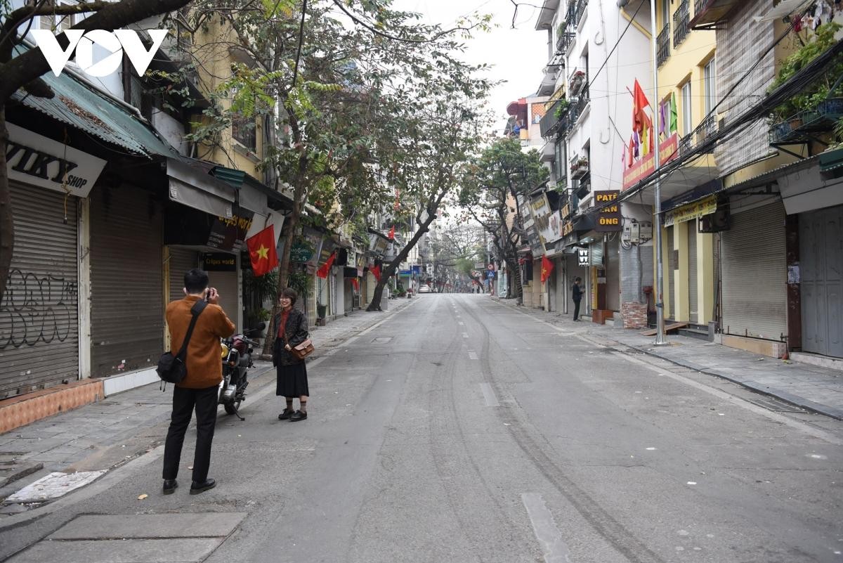Một đôi bạn trẻ chụp hình trên con phố dài hun hút vắng lặng.