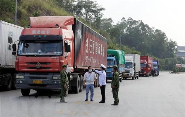 Các lực lượng chức năng kiểm tra thân nhiệt lái xe khi ra, vào khu vực cửa khẩu. (Ảnh Thái Thuần/TTXVN).