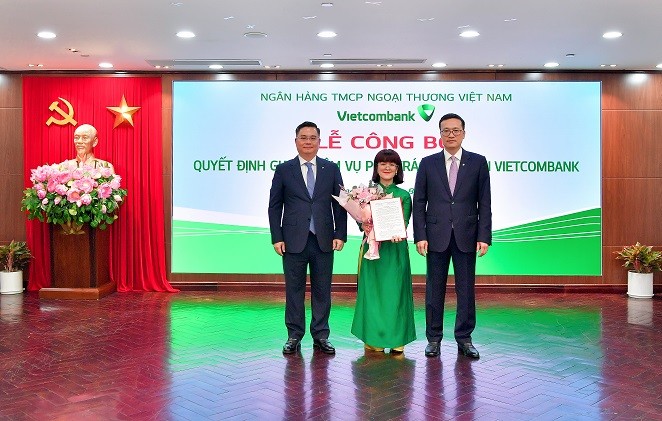 Ông Phạm Quang Dũng, Bí thư Đảng ủy, Chủ tịch Hội đồng Quản trị Vietcombank (bên phải) và Tổng Giám đốc Vietcombank Nguyễn Thanh Tùng (bên trái) trao Quyết định và tặng hoa chúc mừng bà Lê Thị Huyền Diệu- phụ trách Kế toán của Vietcombank