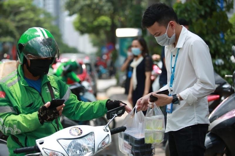 Shipper và khách giữ khoảng cách khi nhận hàng. (Ảnh: Phương Linh)