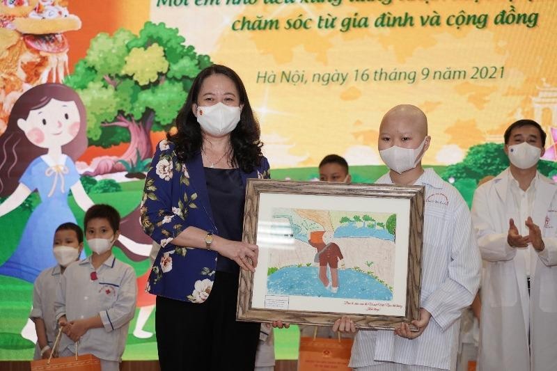 Đại diện bệnh nhi tặng tranh đến Phó Chủ tịch nước Võ Thị Ánh Xuân. Đây là bức tranh bé Chu Ánh Tuyết thực hiện khi tham gia cuộc thi “Vì một Việt Nam tất thắng" dành cho trẻ em ung thư và các trẻ em yếu thế.