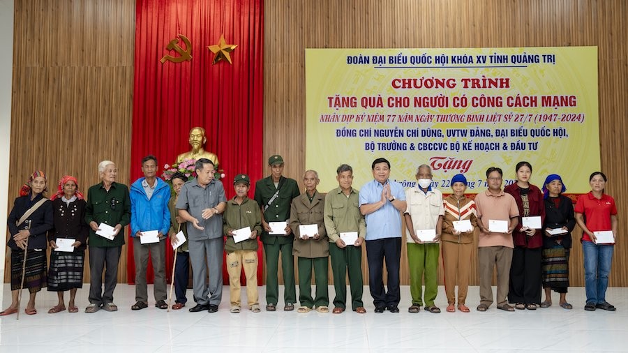Bộ trưởng Nguyễn Chí Dũng trao tận tay từng phần quà cho đại diện các gia đình người có công. Ảnh: Trường Sơn