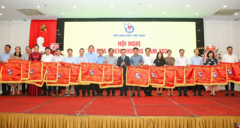 Chủ tịch Hội Nhà báo Việt Nam Lê Quốc Minh trao tặng Cờ thi đua của Hội cho 21 tập thể có thành tích xuất sắc. Ảnh: Sơn Hải.