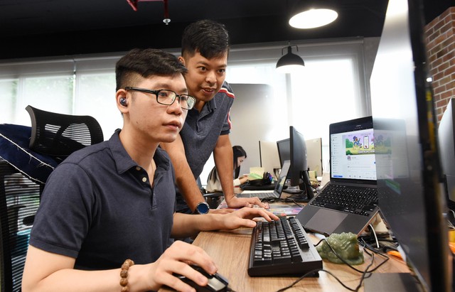 Anh Sơn - "cha đẻ" Bò và Gấu (người đứng) trao đổi công việc với Hà - trưởng nhóm content. Ảnh: Dũng Minh.