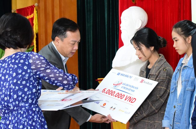 Ông Lê Trọng Minh, đại diện Ban tổ chức trao một số suất học bổng cho các em học sinh, sinh viên tại buổi họp báo