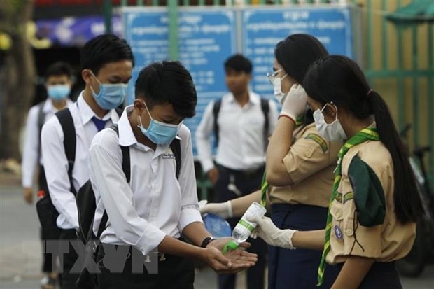 Các học sinh tiến hành sát khuẩn tay nhằm ngăn dịch COVID-19 lây lan, trước khi vào lớp ở Phnom Penh, Campuchia. (Ảnh: AFP/TTXVN).