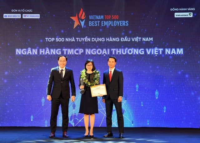 Ông Trương Minh Tiến - Phó tổng giám đốc Viet Research (bên phải) và ông Đặng Tuấn Khánh - Ủy viên Ban Biên tập Báo Kl99ok phiên bản mới (bên trái) trao biểu trưng và chứng nhận Top 500 Nhà tuyển dụng hàng đầu Việt Nam cho bà Tô Thị Phương Dung - Trưởng phòng Chính sách và kế hoạch nhân sự Vietcombank.