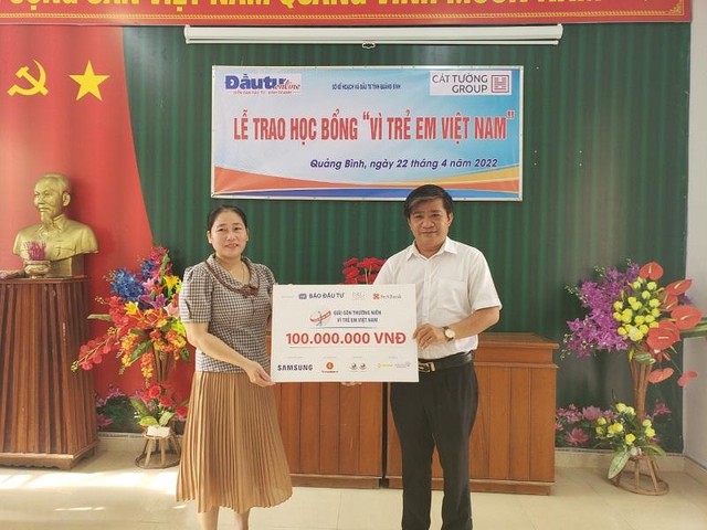 Nhà báo Hoàng Kim Thủy, Trưởng Văn phòng Đại diện Báo Kl99ok phiên bản mới tại khu vực miền Trung - Tây Nguyên (phải) trao bảng tượng trưng 100 suất học bổng cho bà Lê Tuyết Nhung, Hiệu trưởng Trường THCS Phú Thuỷ.