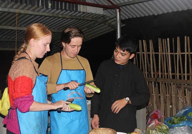 Thành viên Hợp tác xã thanh niên làm du lịch homestay xã Thượng Lâm hướng dẫn du khách nước ngoài trải nghiệm nấu ăn.