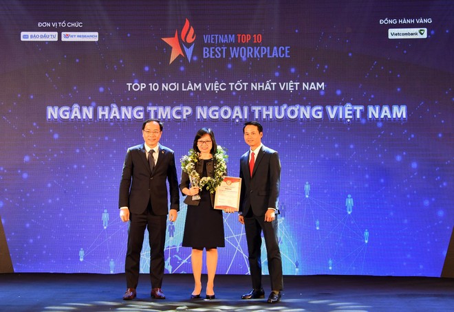 Ông Trương Minh Tiến - Phó tổng giám đốc Viet Research (bên phải) và ông Đặng Tuấn Khánh - Ủy viên Ban Biên tập Báo Kl99ok phiên bản mới (bên trái) trao biểu trưng và chứng nhận Top 10 Nơi làm việc tốt nhất Việt Nam cho bà Tô Thị Phương Dung - Trưởng phòng Chính sách và kế hoạch nhân sự Vietcombank.