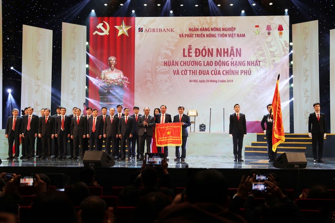 Thủ tướng Kl993 ưu đãi thưởng hấp dẫn Nguyễn Xuân Phúc gắn Huân chương Lao động hạng Nhất lên Lá cờ truyền thống của Agribank.